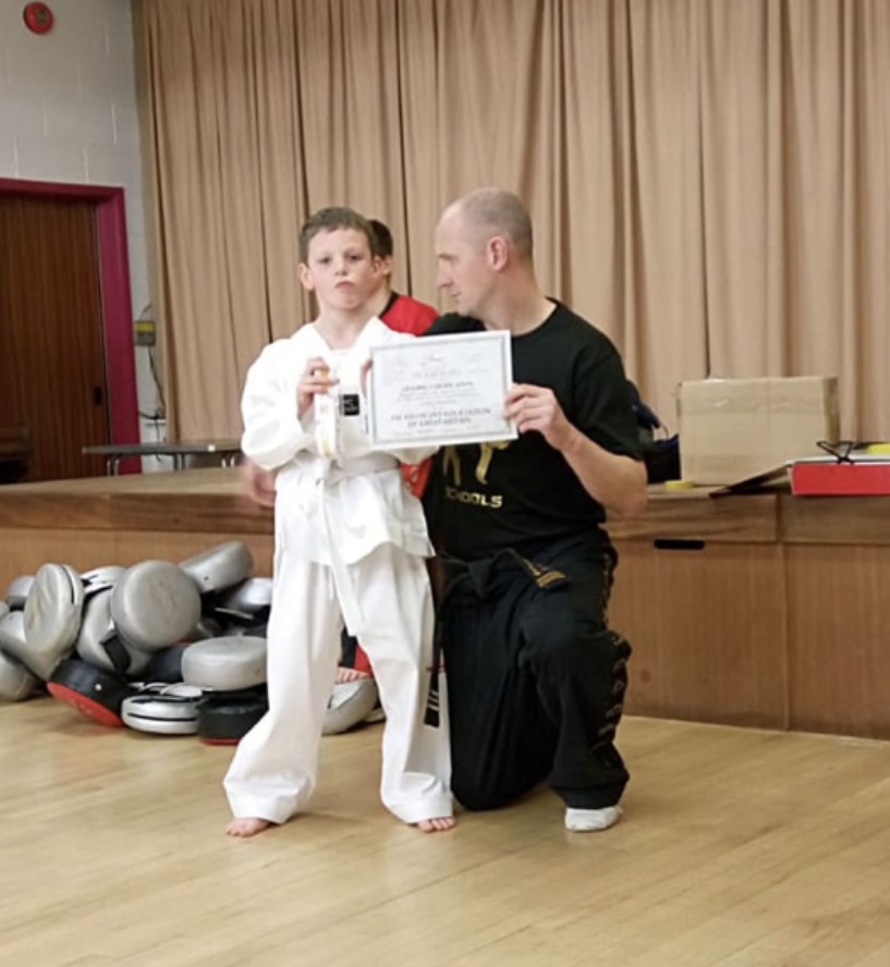 A young Lucas Foster receiving a certificate from Mr Cook — the beginning of an 11-year journey