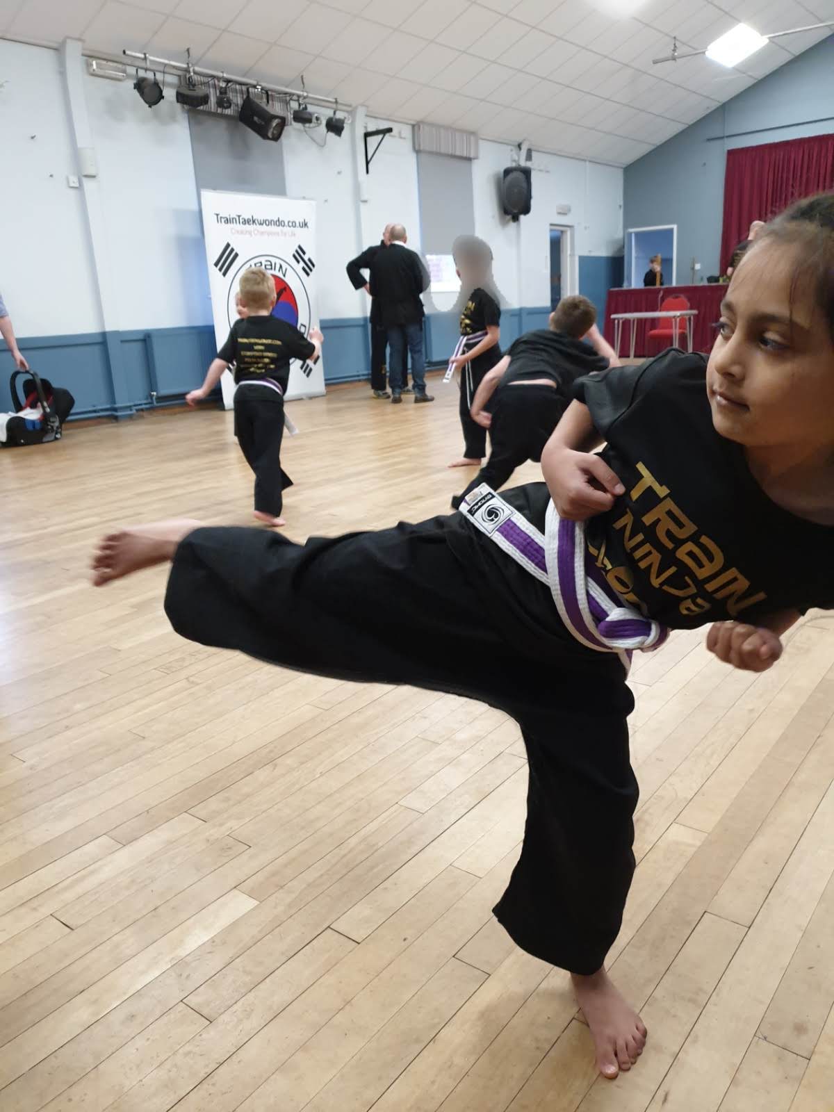 Prisha executing a powerful side kick during a Train Taekwondo class
